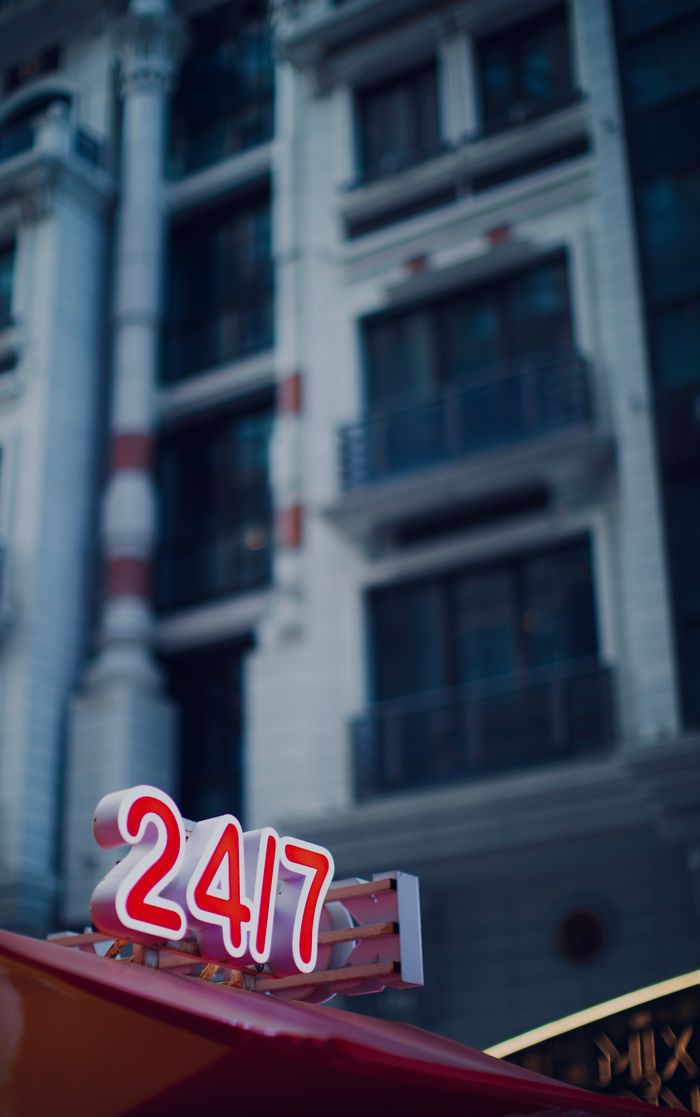Bright 24/7 neon sign in front of a modern building in Baku, Azerbaijan.