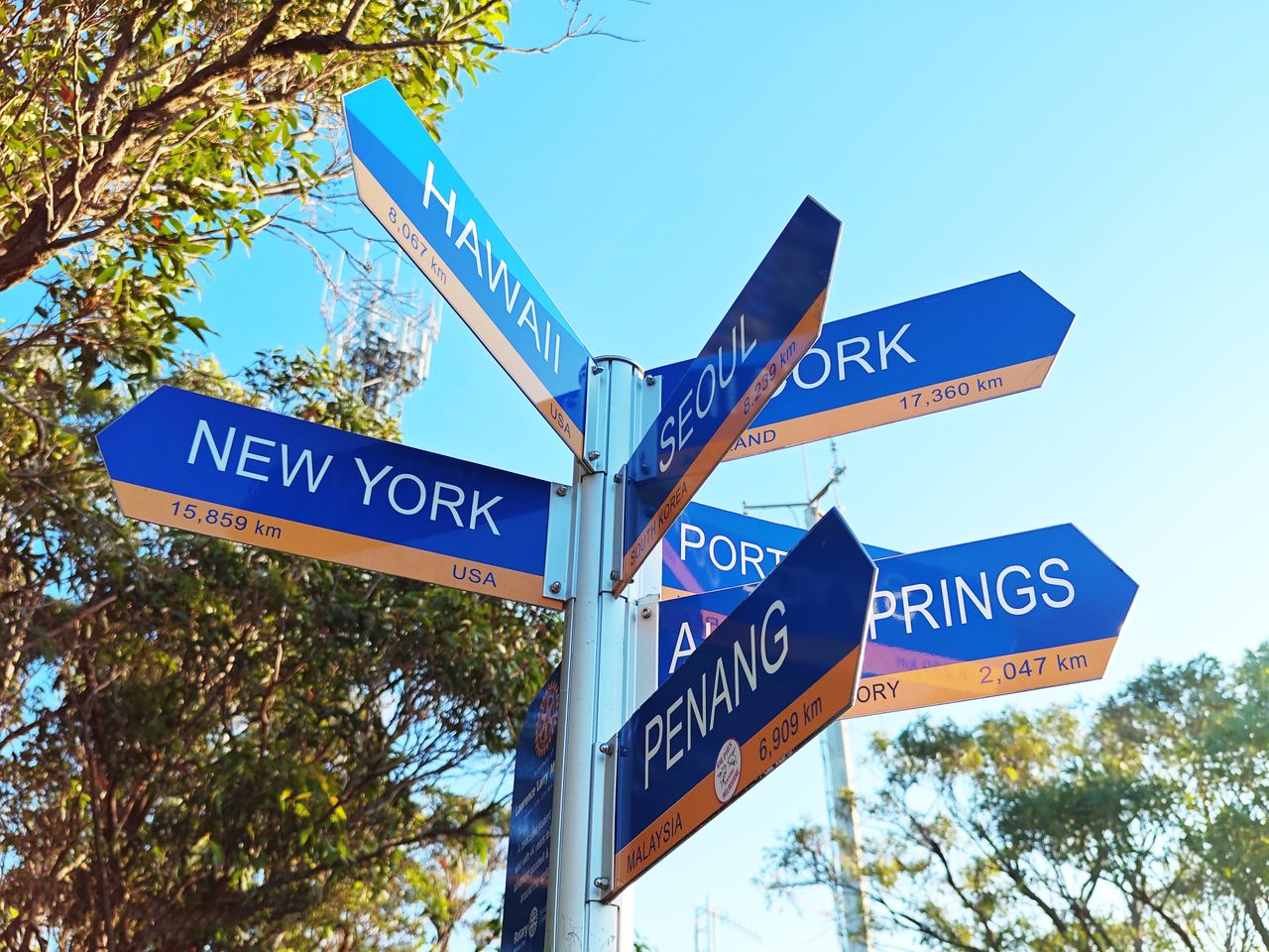 Close-up of a signpost in New South Wales pointing to global cities like New York and Seoul.